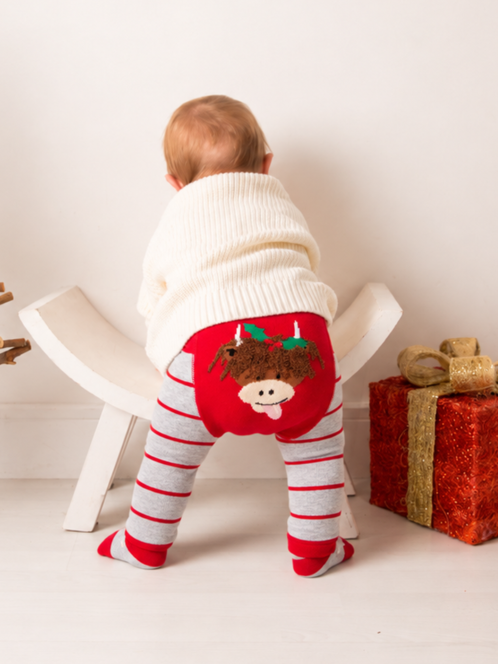 Baby wearing the Hamish Christmas Leggings in grey and red stripe, with the fluffy Hamish face on the red seat panel